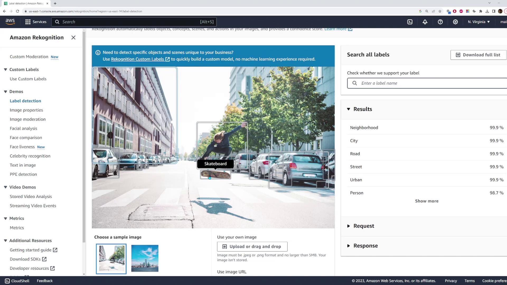 A person is skateboarding on a city street lined with parked cars and trees. The image is part of an Amazon Rekognition demo for label detection.