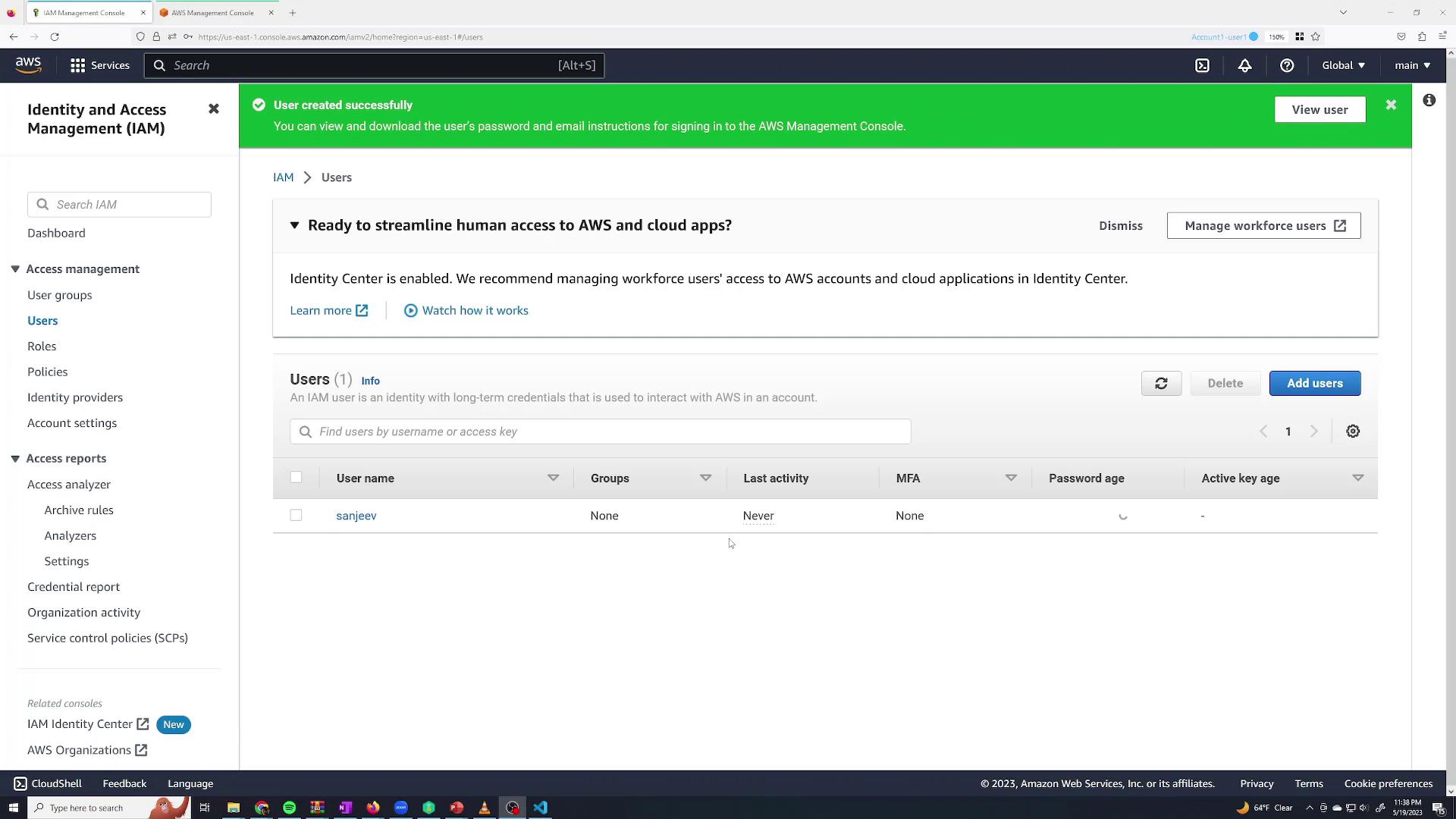 The image shows the AWS Identity and Access Management (IAM) console, displaying a user management interface with a notification about a user being created successfully. It lists one user with details such as username, groups, last activity, and MFA status.