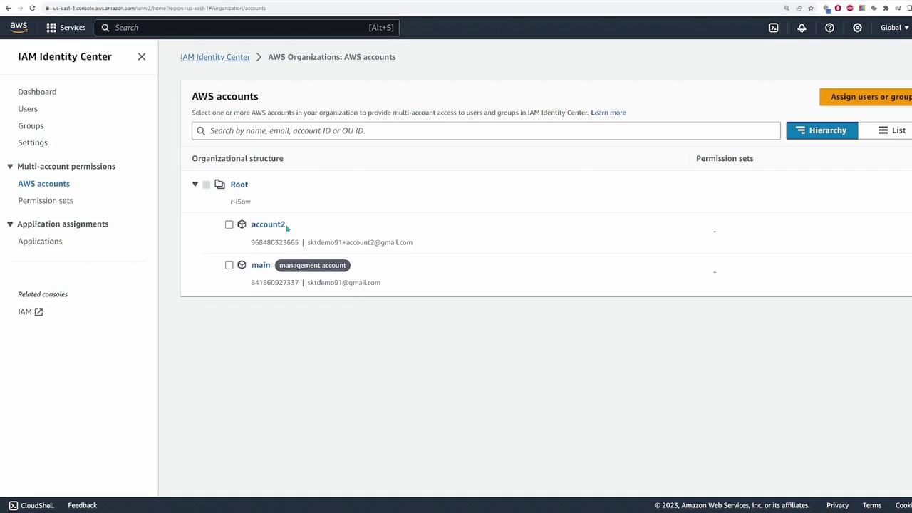 The image shows the AWS IAM Identity Center interface, displaying a list of AWS accounts under an organizational structure with options for assigning users or groups.