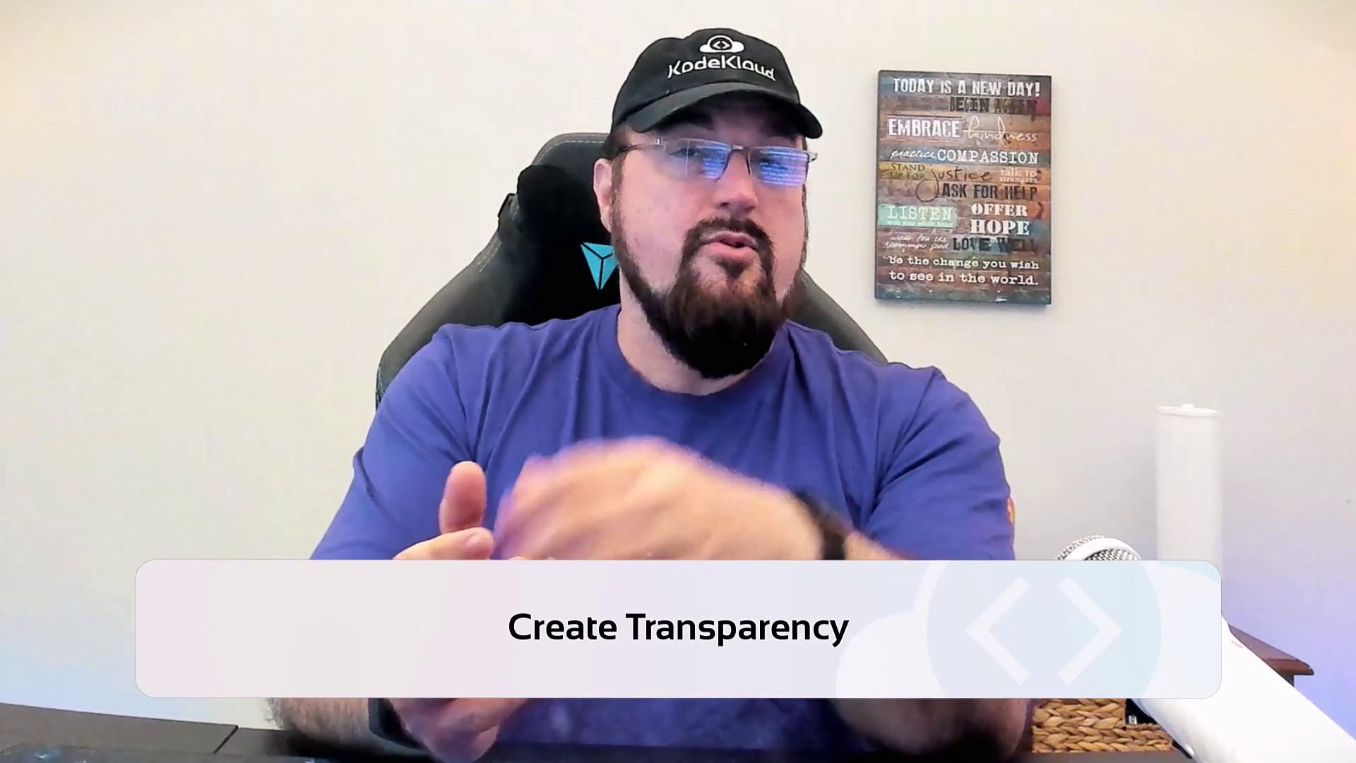 A person wearing a cap and glasses is sitting in front of a wall with a motivational sign, with the text "Create Transparency" displayed at the bottom.