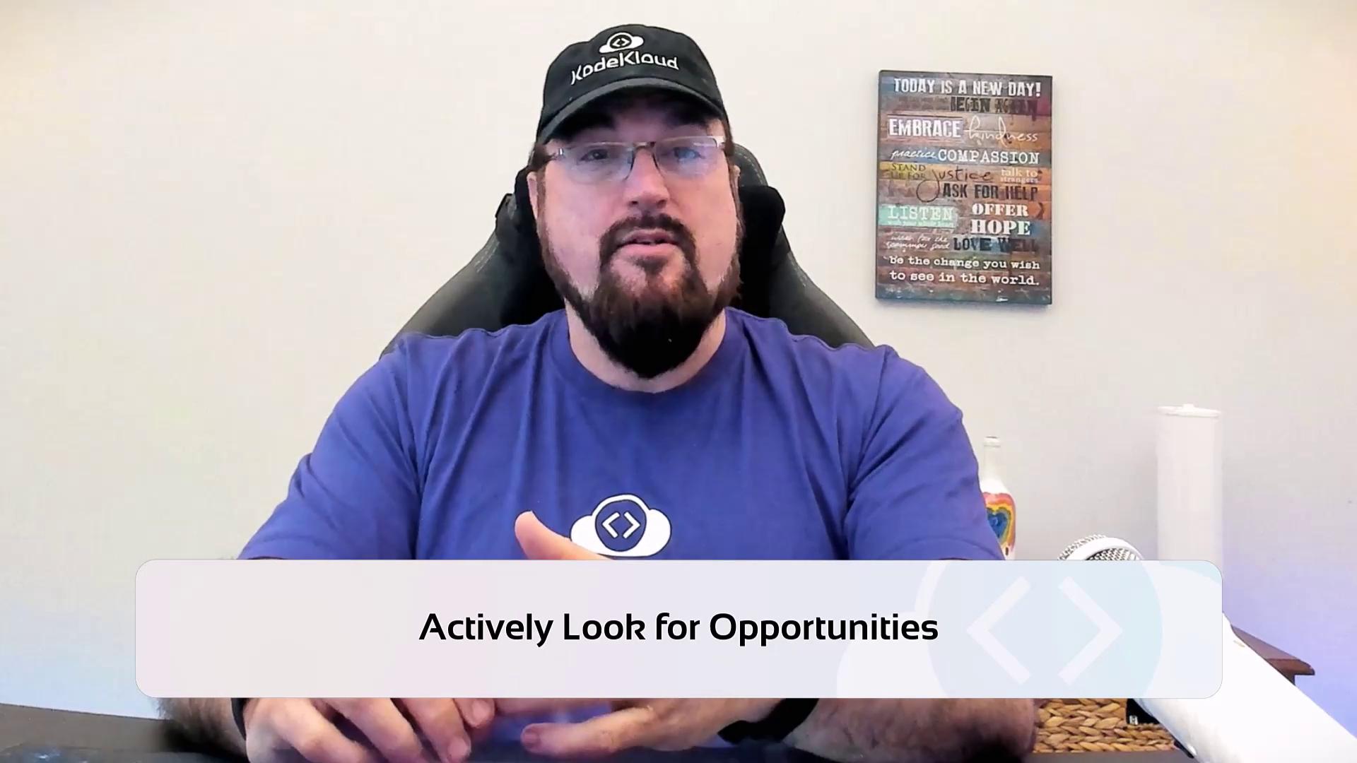 A person wearing a cap and glasses is sitting in front of a motivational sign, with the text "Actively Look for Opportunities" displayed at the bottom.