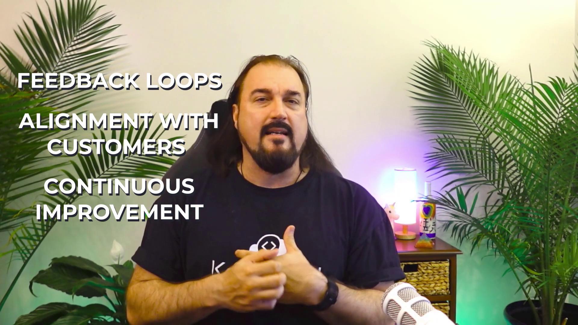 A person is speaking in a room with plants, discussing "Feedback Loops," "Alignment with Customers," and "Continuous Improvement," with a microphone visible.