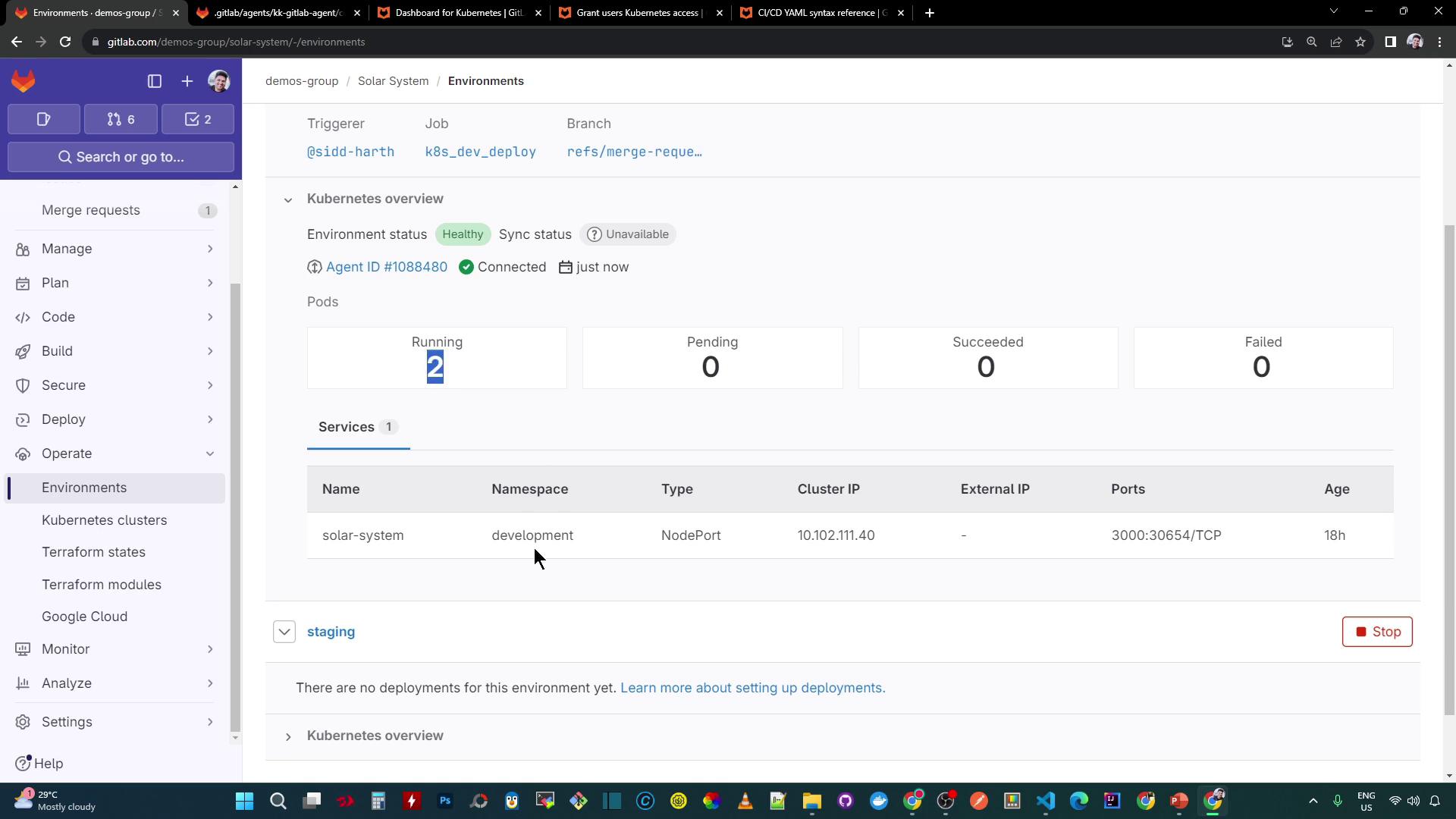 The image shows a GitLab environment dashboard for a project named "solar-system," displaying Kubernetes deployment details such as environment status, pod status, and service information. The environment is marked as "Healthy" with two running pods and no pending, succeeded, or failed deployments.
