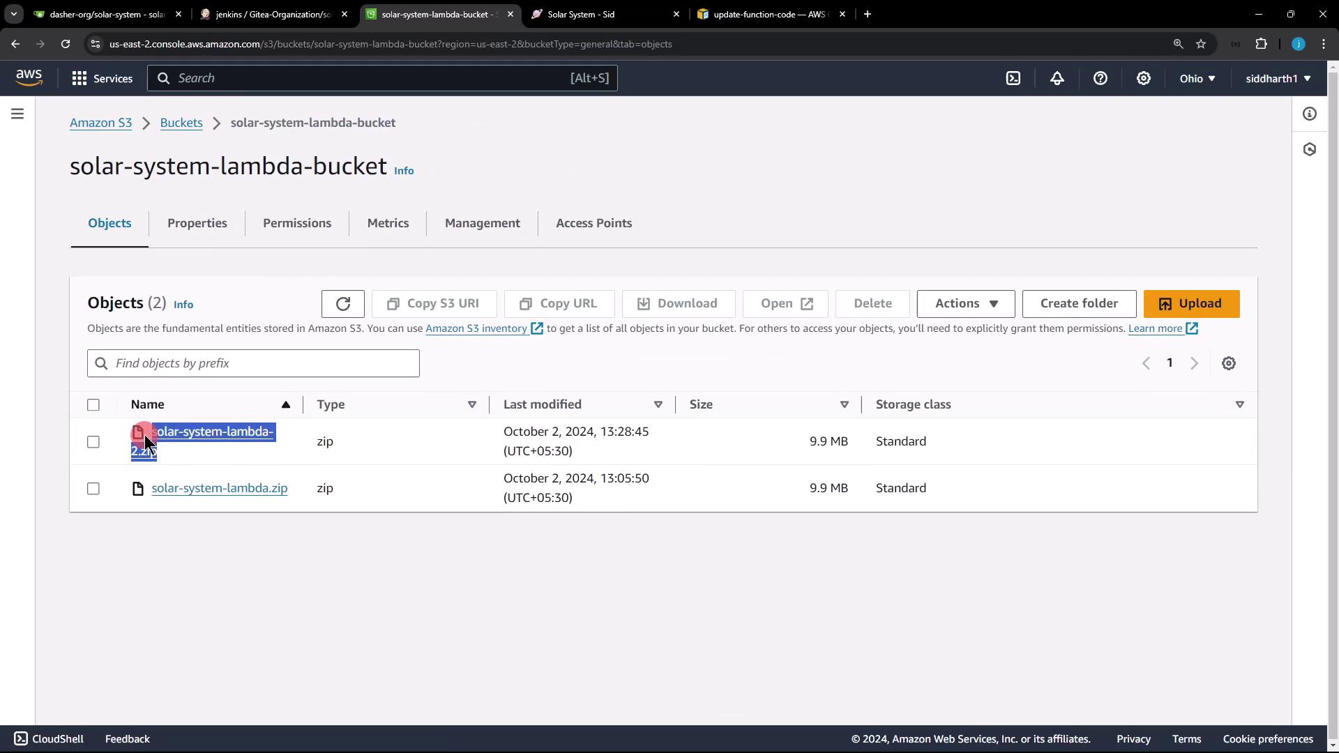 The image shows an Amazon S3 bucket interface with two zip files named "solar-system-lambda-2.2x.zip" and "solar-system-lambda.zip," both with a size of 9.9 MB.