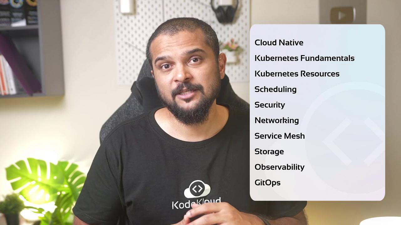 A person is sitting in a room with a list of cloud computing topics displayed, including Kubernetes and GitOps.