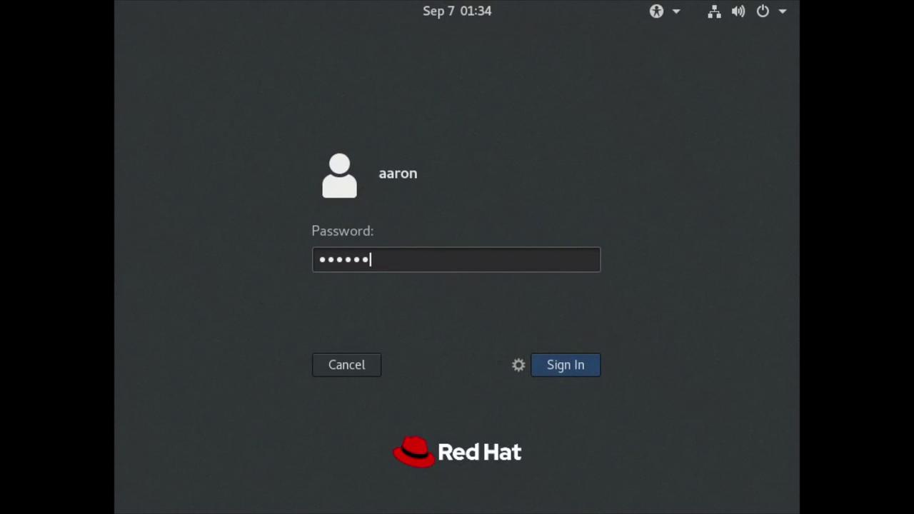 The image shows a Red Hat login screen with a user named "aaron" and a password entry field. The Red Hat logo is displayed at the bottom.